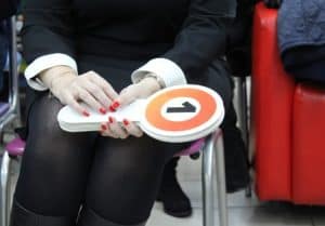 A lady in black dress holding auction bid paddles