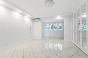 A room with white tiles and glass windows and cabinets with mirrors