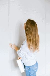 A woman carrying a clipboard and checking a wall surface