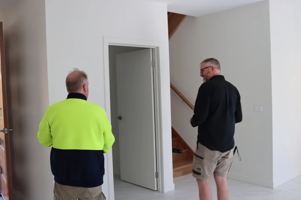 Two registered building inspectors in Melbourne reviewing interior walls and property structure