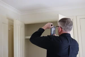 Home inspector photographing interior details inside a wardrobe during a lock-up stage inspection.