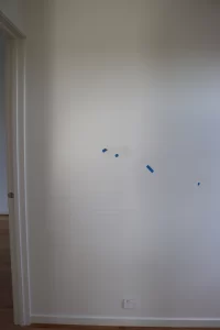 Interior wall marked for defects during a pre-handover PCI building inspection, highlighting issues identified before final settlement.