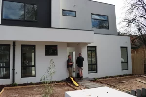 Building inspector meeting homeowner outside a newly built house during a Melbourne building and pest inspection