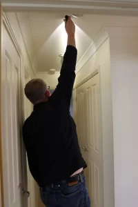Buy Wise inspector checking a ceiling light fixture during a building inspection