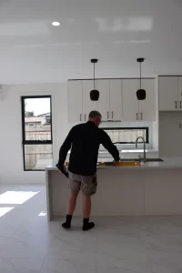 Buy Wise inspector checking a kitchen bench for level during a pre-handover inspection