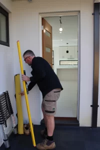 Buy Wise inspector checking a door frame for level during a pre-handover inspection