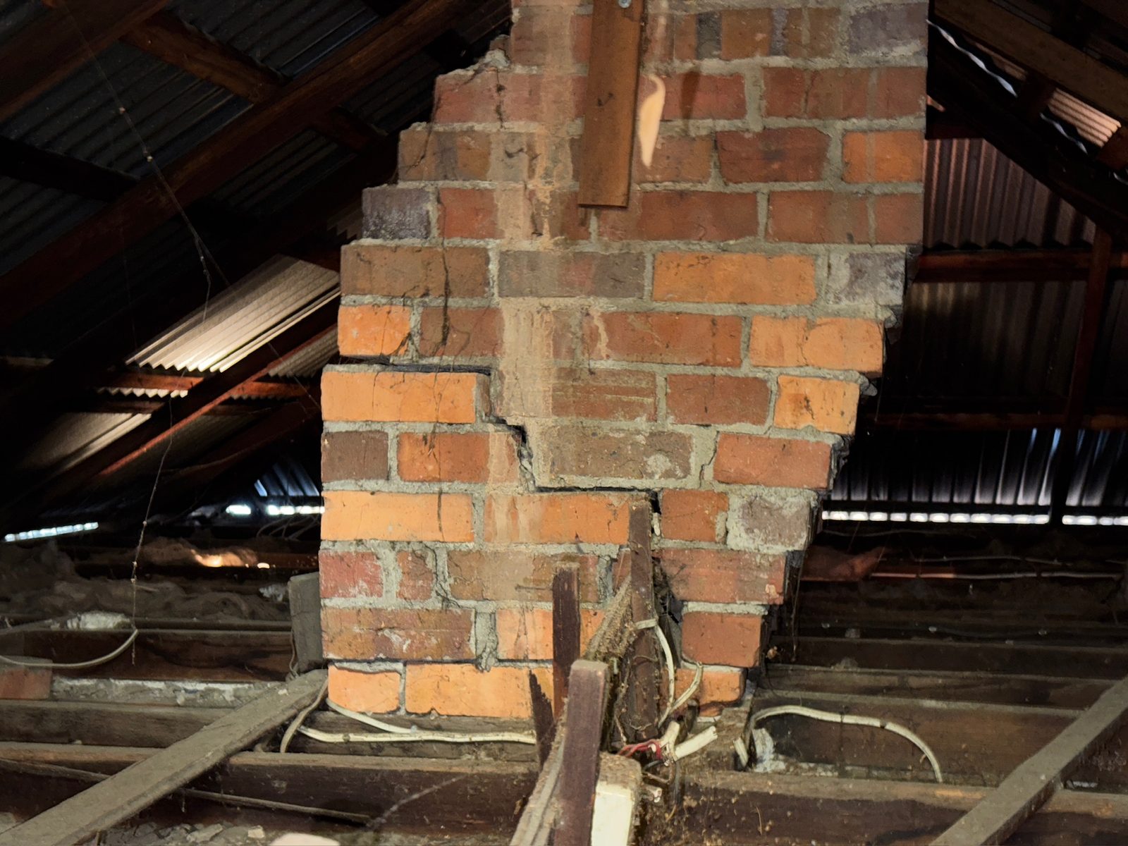 Structural cracking in a brick chimney found in a roof cavity during a building inspection